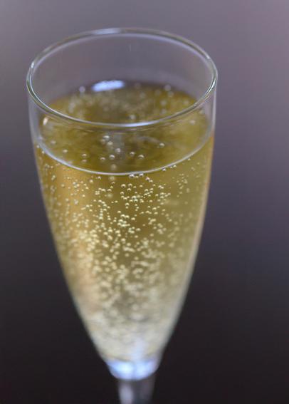 A close-up of a glass filled with sparkling golden beverage, showcasing bubbles rising to the surface.