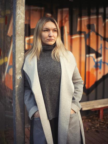 Junge Frau, die an der Metallstütze einer Bushaltestelle lehnt