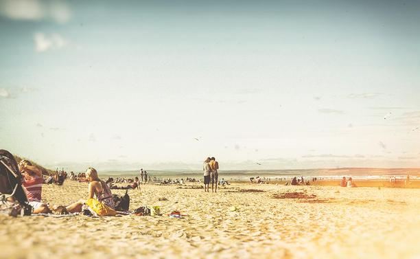People on the beach at St Andrews in Scotland near the sea in the summer in vintage seventies look.