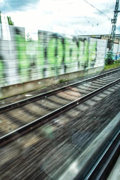 Aus dem Zugfenster heraus das Parallelgleis fotografiert. Durch  die längere Belichtungszeit sieht man den Gleisschotter verwischt und man hat den Eindruck von Geschwindigkeit. 