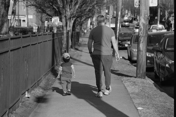A man and his son walking down the sidewalk