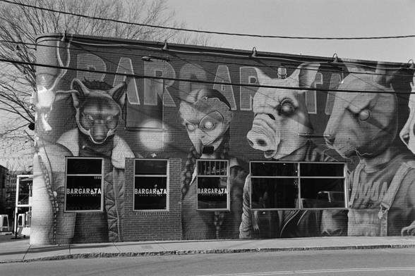 A bar with giant masked characters painted on its side
