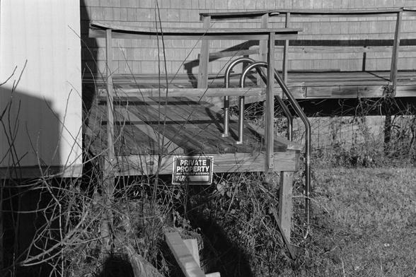 A pool ladder hanging on an old deck…into grass