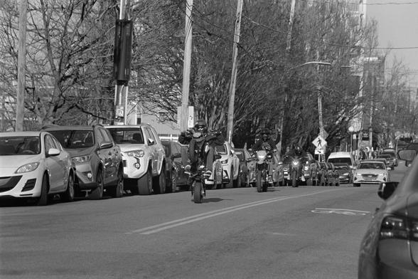 A group of motorcyclists showing off. The one in front doing a wheelie.