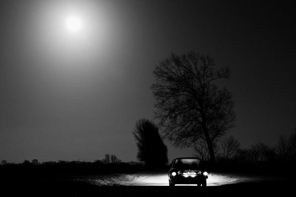 Ein Auto, das im Mondschein eine einsame, dunkle Straße entlangfährt. Hier kann man schon ein paar Sachen erahnen, die im nächsten Bild deutlicher werden, aber trotzdem leider zu wenig verständlich bleiben ...