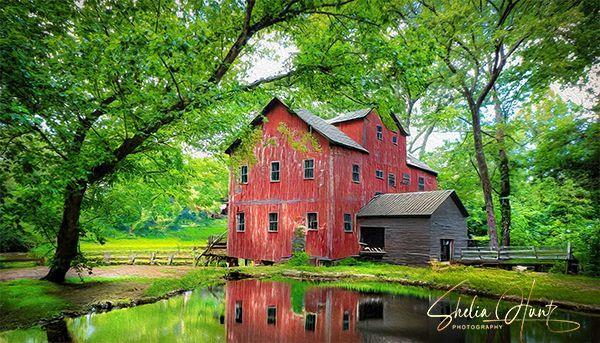 Panoramic view of Jones Mill, a historic grist mill on a country lane in Middle Tennessee, reflected in the calm waters of a pond, surrounded by serene natural beauty, with a textured overlay enhancing the historic and artistic feel of the photograph.   From the Fine Art Gallery of Shelia Hunt at Shelia-Hunt.pixels.com