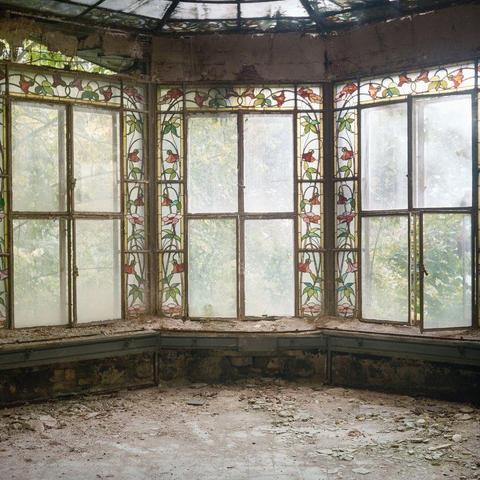 three tall windows, bay window, with glass roof. there is stained glass of floral patterns 