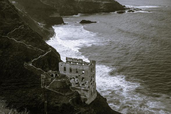 Black and white photo of abandoned ruins at Camino de Rambla de Castro against the backdrop of North Atlantic Ocean waves crashing into Tenerife North cliffs 
Captured by Komeil Karimi