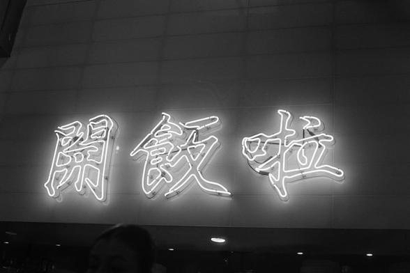 Neon signs of 3 characters in an Asian language (the meaning of which I have no clue, I hope it’s not obscene) on the wall of a street food restaurant I had lunch in