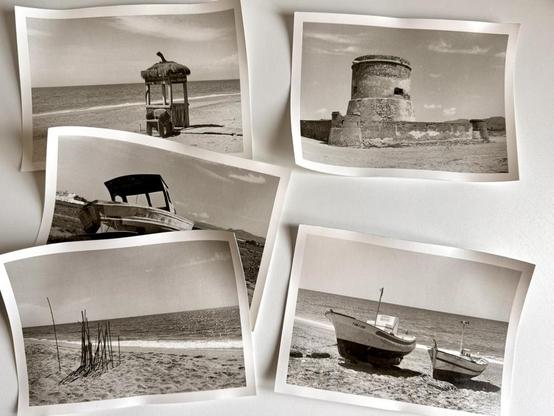 Five darkroom prints on fibre paper laid out on a worktop