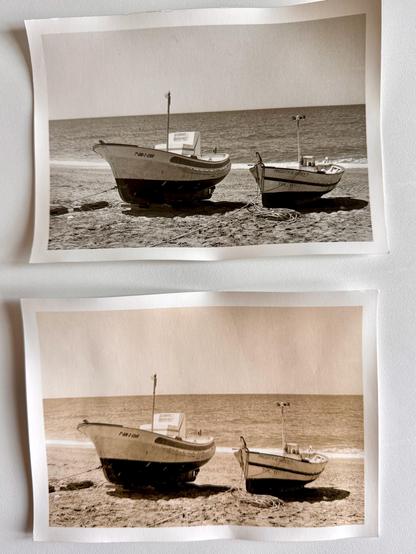 A black and white darkroom print of two boats on a sandy beach. There are two versions of the same print; a normal print and a lith print. The with print has yellow/brown tones.