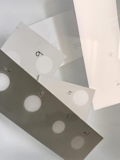 Photographic paper test strips exposed to darkroom safelights. The Retrobrom test strip is severely affected and has turned dark grey. 