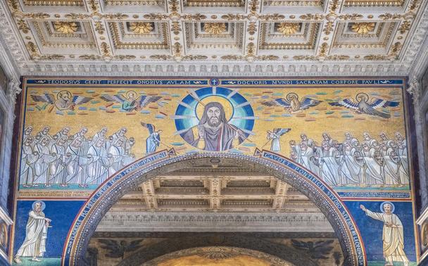 The triumphal arch in the Basilica of St Paul Outside the Walls in Rome Italy. It is a mosaic featuring Christ in the middle flanked by four winged evengelists and the 24 elders of Revelation. Below are Peter on the right and Paul on the left. 