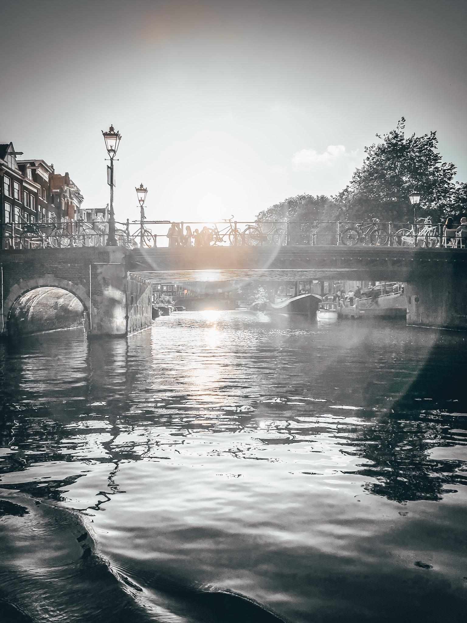 🧭 Eine ruhige Szene mit einer alten Steinbrücke über einem Kanal. Auf der Brücke stehen Fahrräder und ein paar Menschen. Die Sonne scheint tief und wirft warmes Licht durch die Brückenbögen aufs glitzernde Wasser. Im Hintergrund: Bäume, klassische Stadtgebäude – typisch für eine Stadt mit vielen Kanälen. Atmosphäre: friedlich, idyllisch, lebendig.
Die Sonne spiegelt sich im Objektiv. Die Bildbearbeitung verstärkt den Effekt. 
Bild ist in schwarz-weiß 
🧭 A quiet scene with an old stone bridge over a canal. There are bicycles and a few people on the bridge. The sun shines deeply and casts warm light through the bridge arches on the glittering water. In the background: trees, classic city buildings - typical of a city with many canals. Atmosphere: peaceful, idyllic, lively.
The sun is reflected in the lens. Image processing enhances the effect.
Picture is in black and white 🧭 Eine ruhige Szene mit einer alten Steinbrücke über einem Kanal. Auf der Brücke stehen Fahrräder und ein paar Menschen. Die Sonne scheint tief und wirft warmes Licht durch die Brückenbögen aufs glitzernde Wasser. Im Hintergrund: Bäume, klassische Stadtgebäude – typisch für eine Stadt mit vielen Kanälen. Atmosphäre: friedlich, idyllisch, lebendig.
Die Sonne spiegelt sich im Objektiv. Die Bildbearbeitung verstärkt den Effekt. 
Bild ist in schwarz-weiß 
🧭 A quiet scene with an old stone bridge over a canal. There are bicycles and a few people on the bridge. The sun shines deeply and casts warm light through the bridge arches on the glittering water. In the background: trees, classic city buildings - typical of a city with many canals. Atmosphere: peaceful, idyllic, lively.
The sun is reflected in the lens. Image processing enhances the effect.
Picture is in black and white