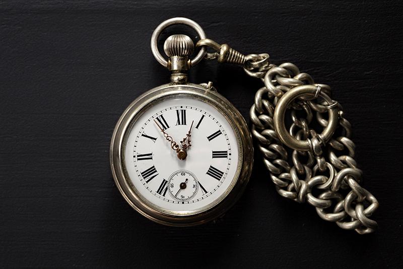 Vintage pocket watch with chain on black background