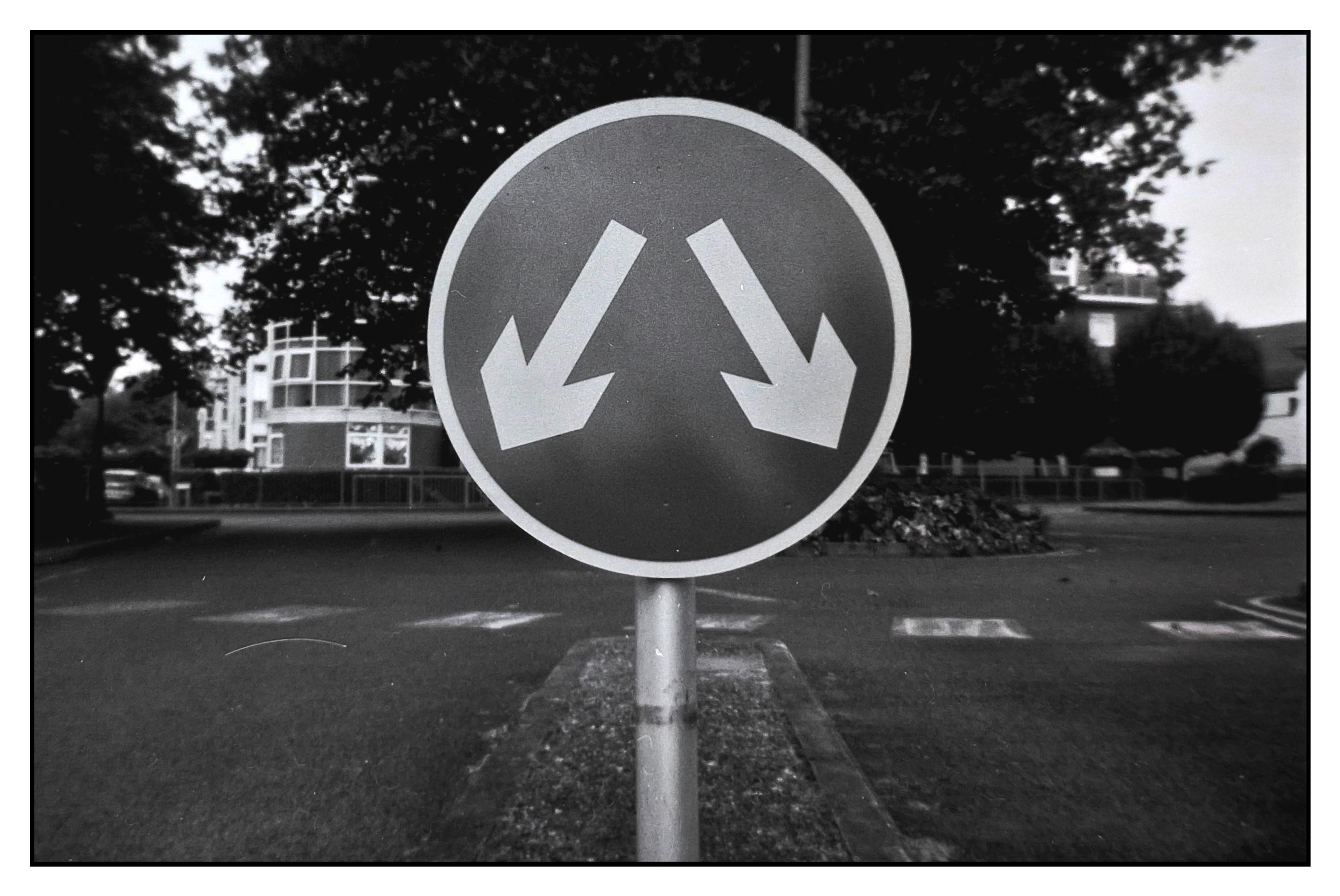 A grainy monochrome analogue image of a two way road sign