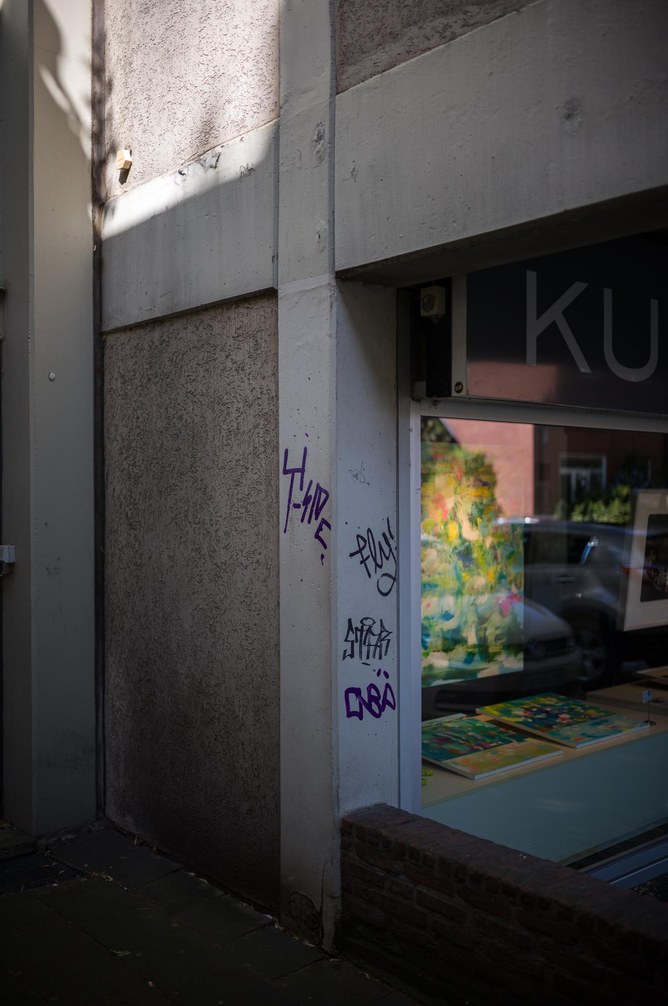 corner, shadow, shop window and graffiti tags at the concrete column beside the shopwindow