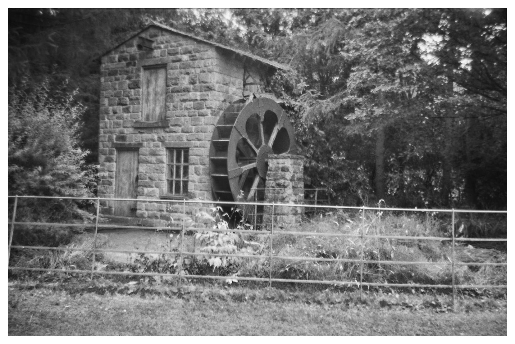 A grainy monochrome photo of a reconstructed watermill in Roundhay Park, Leeds.