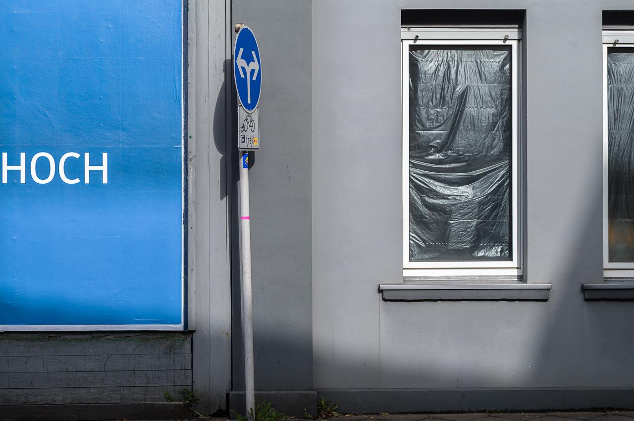 billboard,  blue, grey facade, shadow, blue traffic sign, covered window
