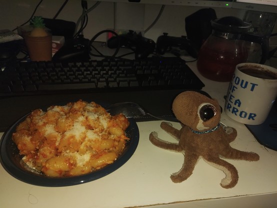 A plush octopus next to a bowl of pasta: Gnocchi with Aglio, Oli, e Peperoncino and (vegan) grated cheese