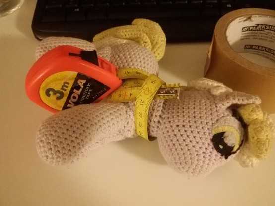 Plushie Mazie wrapped in a measuring tape