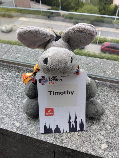 Happy plush donkey with a conference badge that says "Timothy' on it that is almost as high as he is.