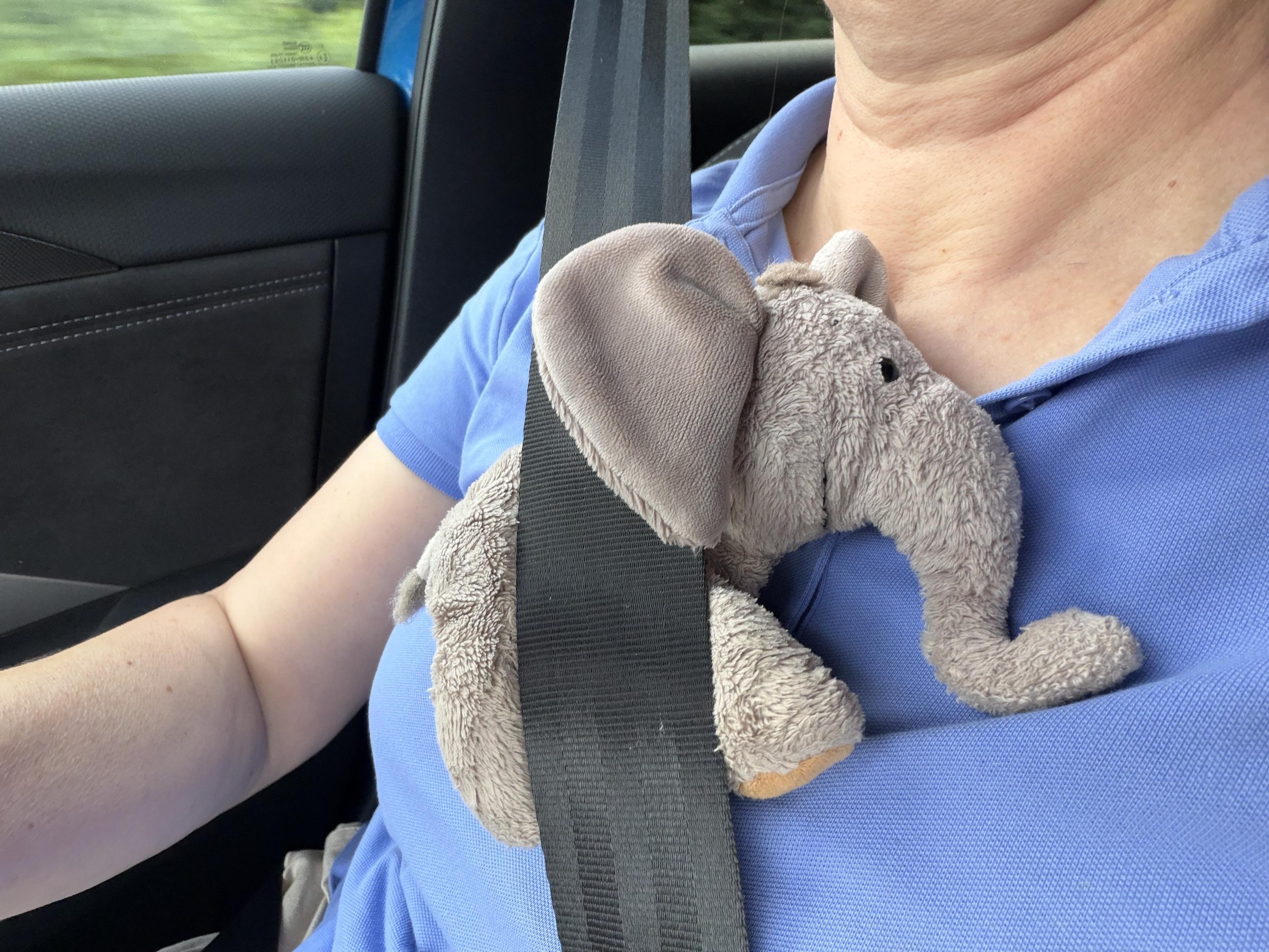 Ein Plüschelefanty kuschelt sich sehr lieb an Bibo, der Sicherheitsgurt im Auto hält ihn an ihre Brust gedrückt