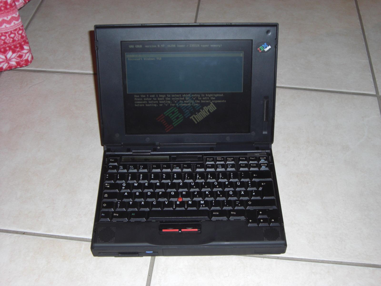 Ein altes ThinkPad 760L auf dem Boden stehend. Es ist der GRUB-Bootloader mit IBM ThinkPad-Theme zu sehen.
