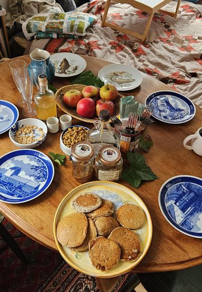 A table set with mismatched plates, apples, lupini beans and pancakes (seen from the side)
