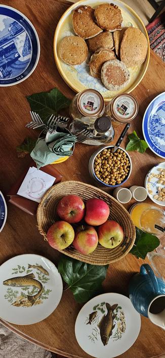 A table set with mismatched plates, apples, lupini beans and pancakes (seen from above)