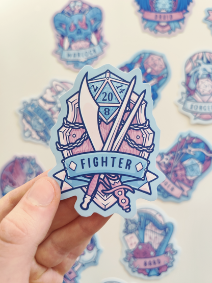 hand holding up a sticker of the fighter, showing crossed swords and a shield with d20 in the background