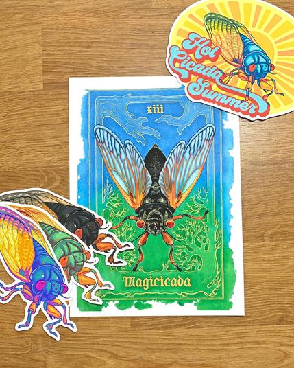 Photo of cicada stickers in multiple colors, a Hot Cicada Summer sticker, and a small tarot-style card of a periodical cicada on a green and blue background with a gold border in the style of tree branches and roots