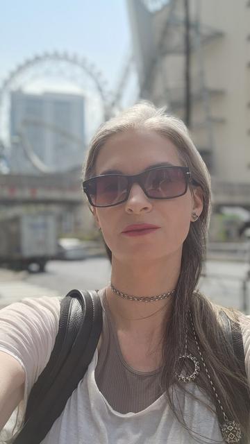 Katherine poses in front of the Big O Ferris wheel in Tokyo Dome City. She wears Xover0's solid sterling silver Sentāresu lariat necklace, named for its resemblance to the centerless structure behind her.