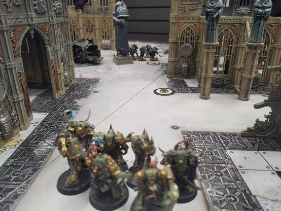 Photo d'un groupe de Marine de la Peste prêts à avancer vers un objectif. Au loin une unité de scouts Space Marine de la Raven Guard