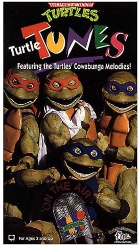 VHS tape cover reading "Teenage Mutant Ninja Turtles, Turtle Tunes, Featuring the Turtles' Cowabunga Melodies!" Pictured are terrifying live-action costumes of the four ninja turtles with bugged-out eyes and way-too-visible teeth.