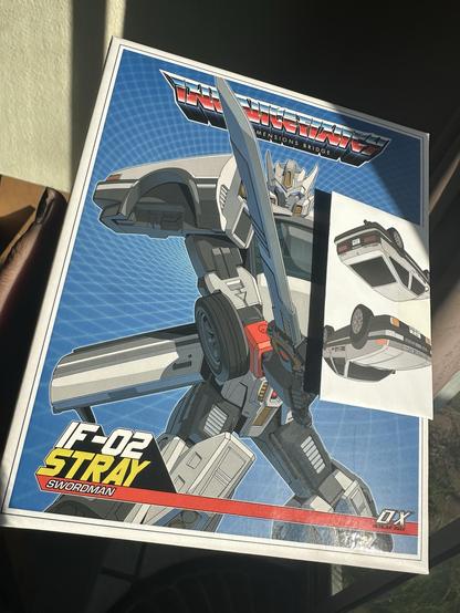 The image features a collectibles box for a toy robot, prominently displaying an illustrated character wielding a sword against a blue background. A small cut-out section reveals another image of a car, hinting at a transformation feature.