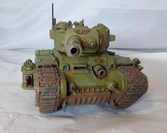 A big, green, somewhat dirty tank with a lot of guns. Front view.