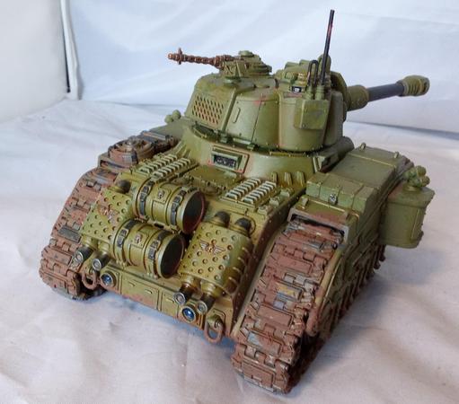A big, green, somewhat dirty tank with a lot of guns. Rear view.