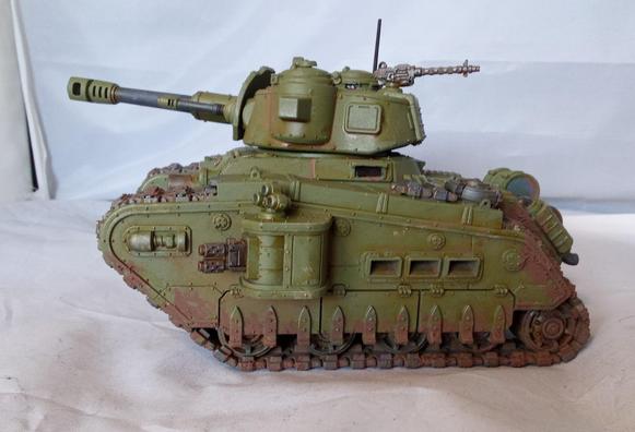 A big, green, somewhat dirty tank with a lot of guns.Side view.