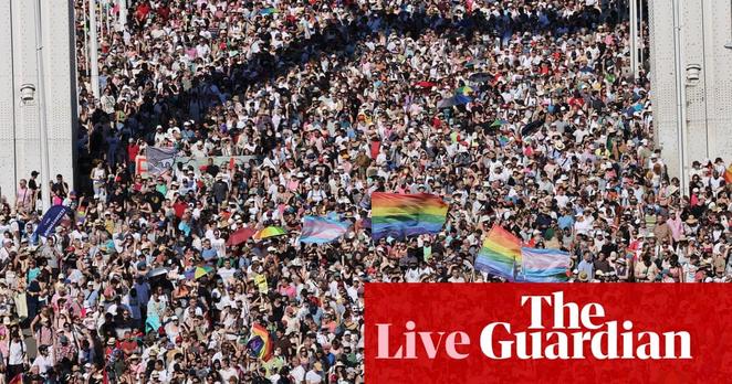 large crowd in the streets waving rainbow flags
