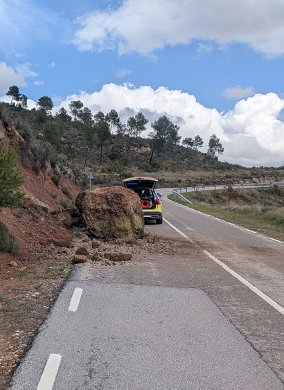 rock the size of a car blocks a road with a police car warning passers by