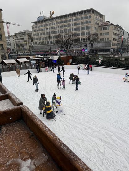 Snow covered ice rink with people ice skating