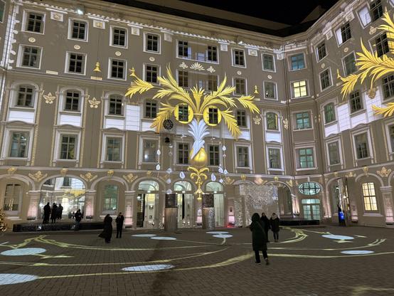Leafy gold cat mask projected onto the side of a 5 story building that formed one side of a courtyard 
