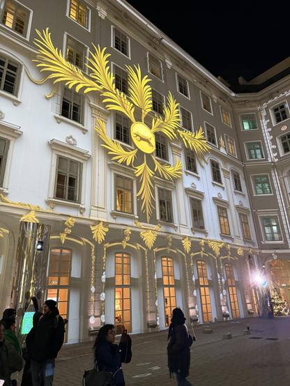 Leafy emblem projected onto the side of a 5 story building that formed one side of a courtyard 