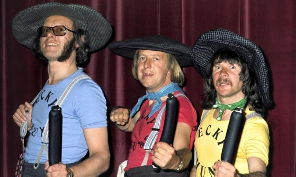 Graeme Garden (1943-), Tim Brooke-Taylor (1940 – 2020),  and Bill Oddie (1941), holding black puddings from the Kung Fu Kapers/Ecky Thump episode of The Goodies.