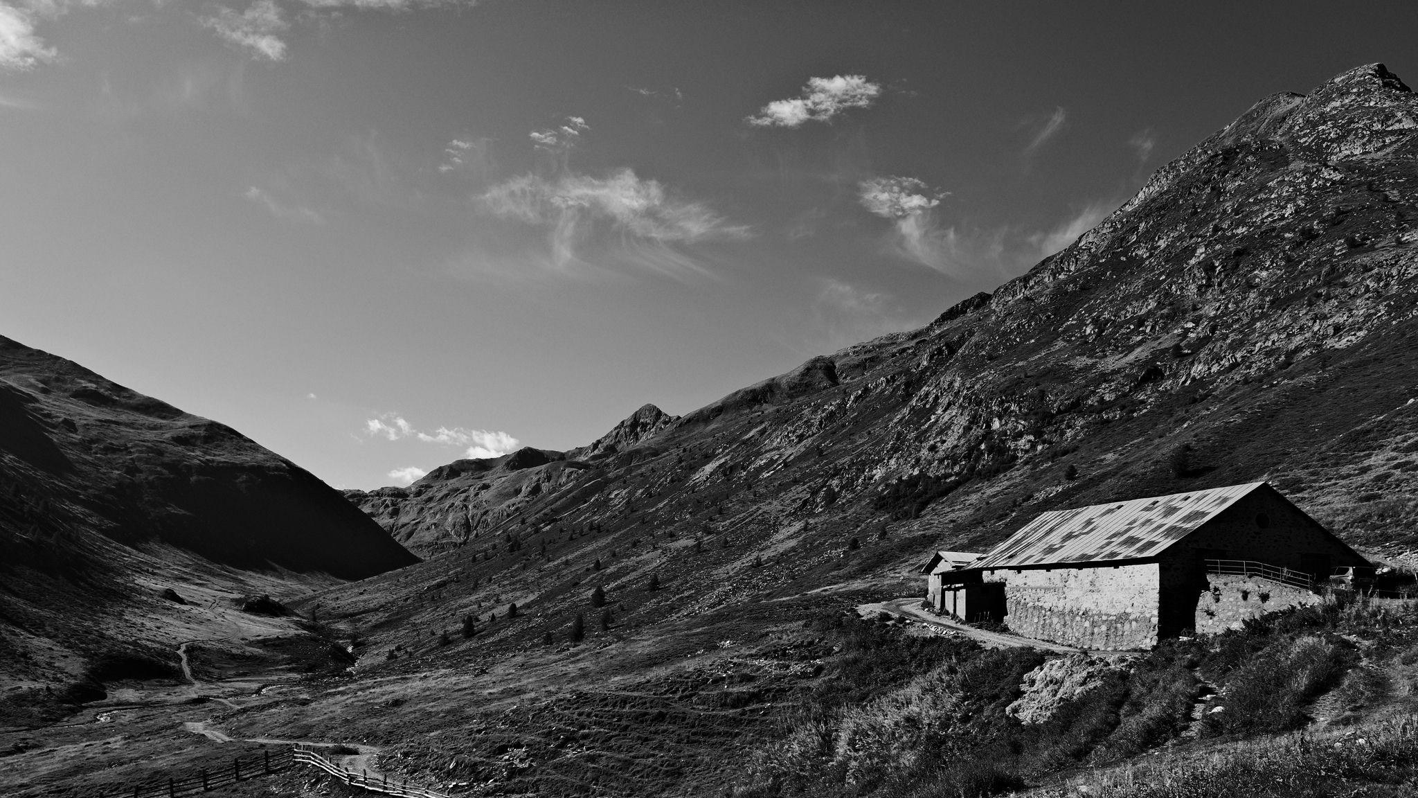 Black and white shot of a stable up in a alpine valley.