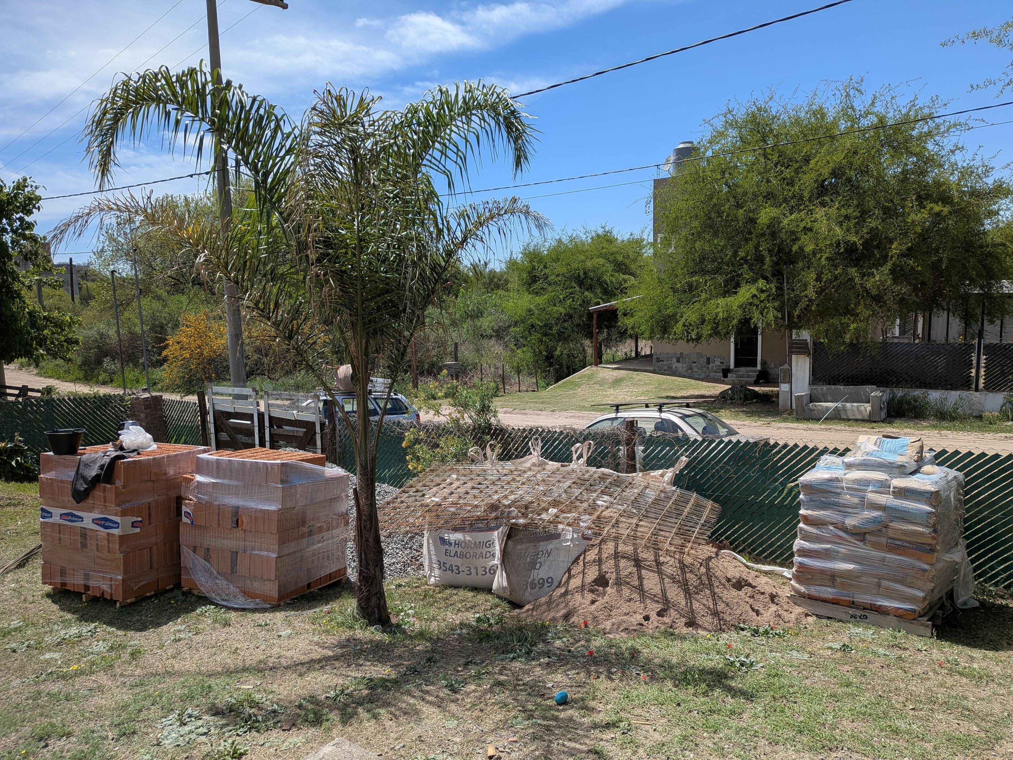 A bunch of building materials, bricks, bags of concrete etc in a garden