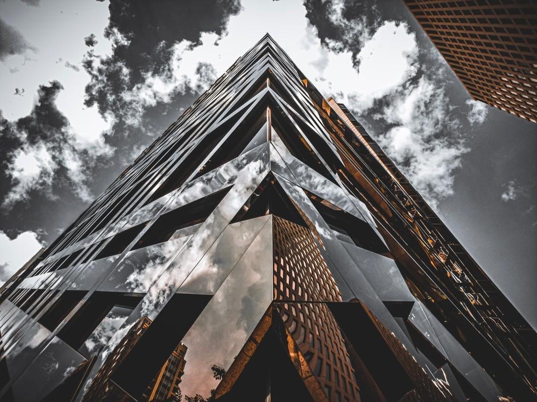a building corner with clouds reflecting in the building