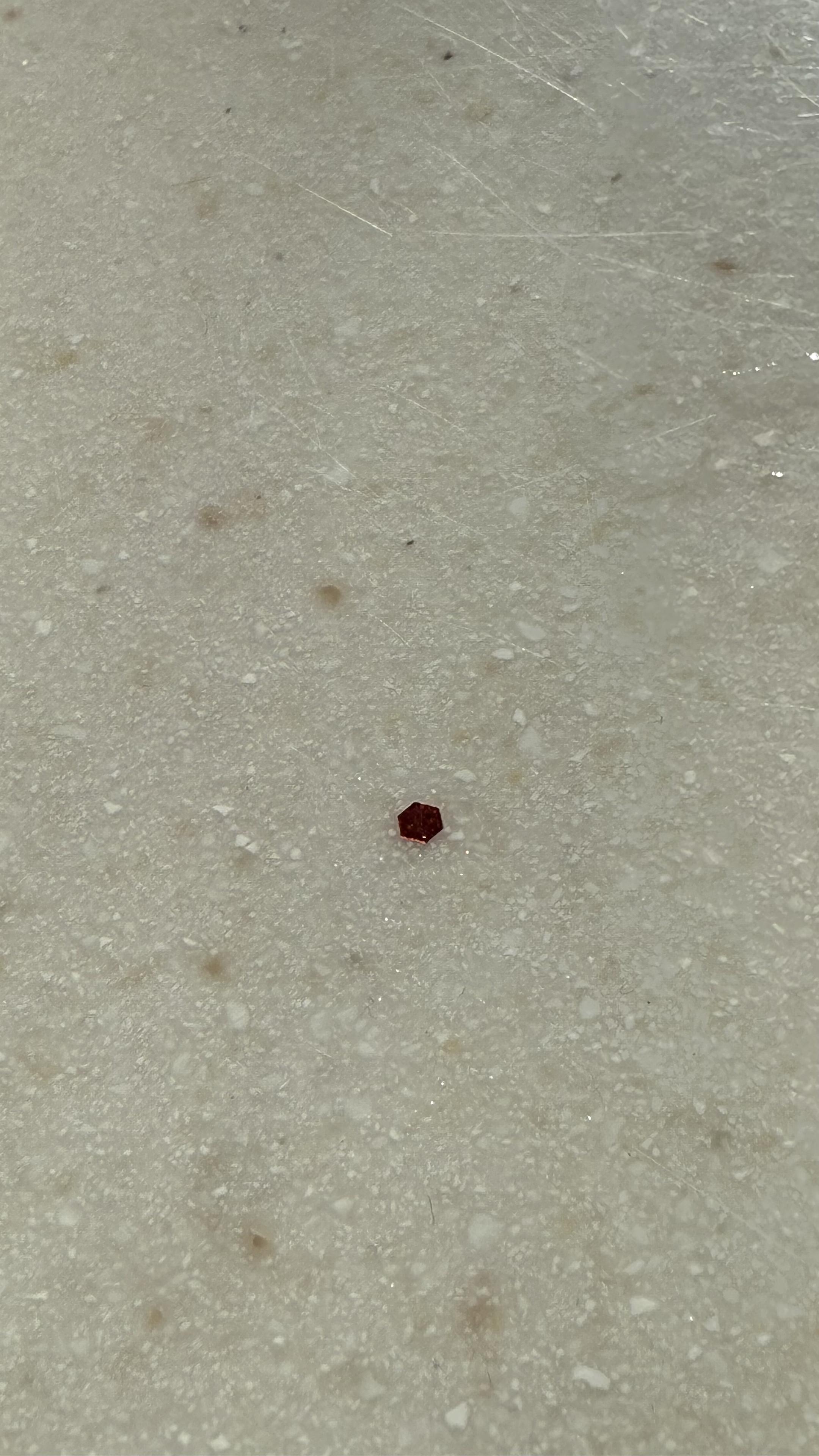 A hexagonal piece of red metallic glitter.