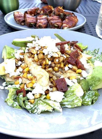 The mentioned salad with the mentioned bacon-wrapped, cream-cheese-stuffed jalepenos in the background.